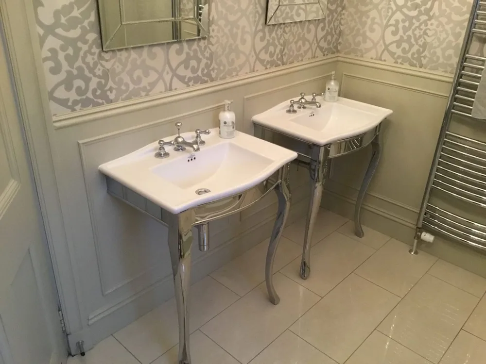 Traditional twin basins on chrome stands with a heated towel rail